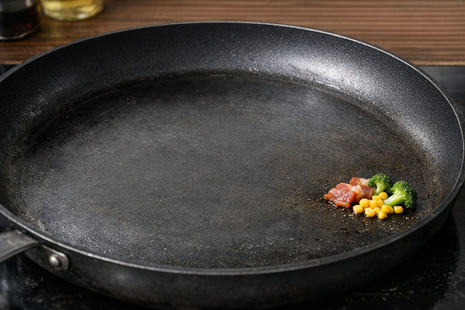 少量の食材が広大なフライパンの端でポツンと焼かれている様子